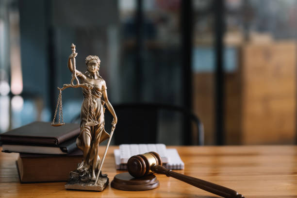 Figura de la justicia, códigos y mazo sobre un escritorio